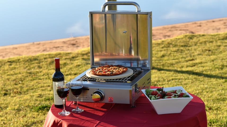Portable BBQ set up beside a caravan at camp